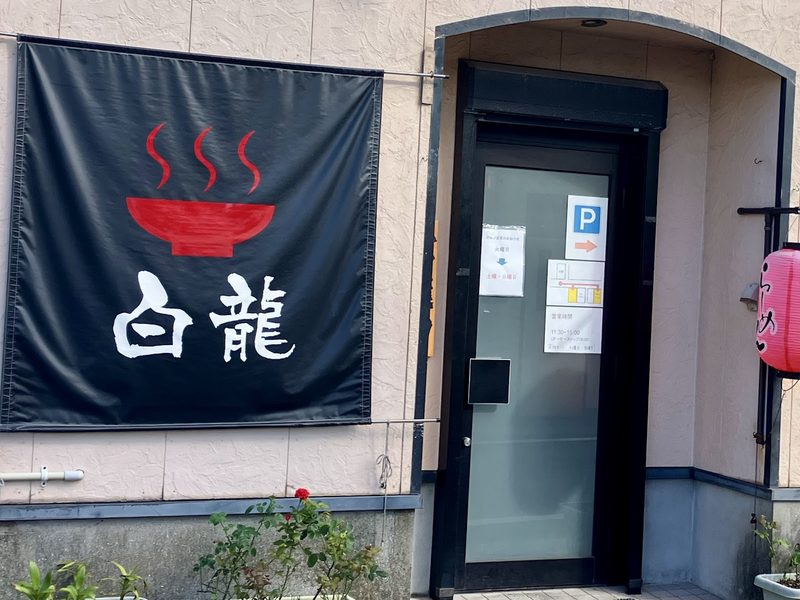 赤いどんぶりと「白龍」の文字を染めた紺色の幕がかかる店の入口