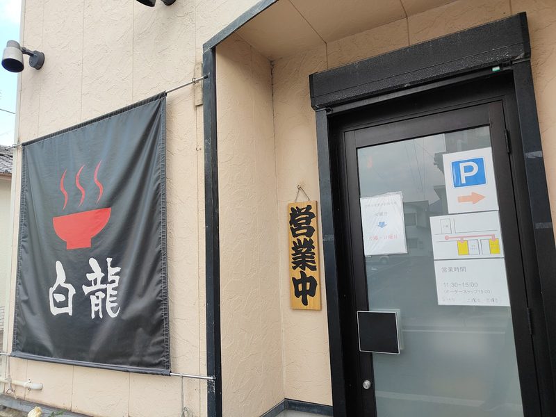 「白龍」の幕と木の「営業中」札、ガラス扉の入口