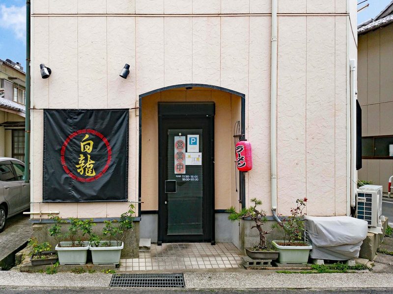 赤い輪の中に「白龍」と書いた黒い幕と、アーチ形の入口がある白龍の店構え
